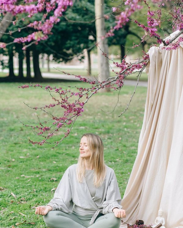 Woman meditating peacefully in a calm green environment.